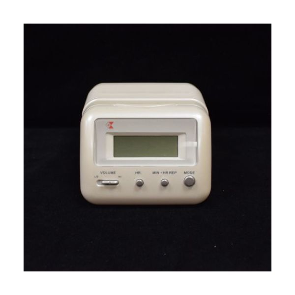 Square white plastic clock with LCD display and buttons for volume toggle, hours and minutes, and changing clock mode.